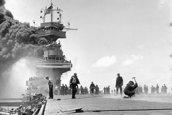 Black and White Photograph of the warship Yorktown under attack. There are dozens of men on deck.
