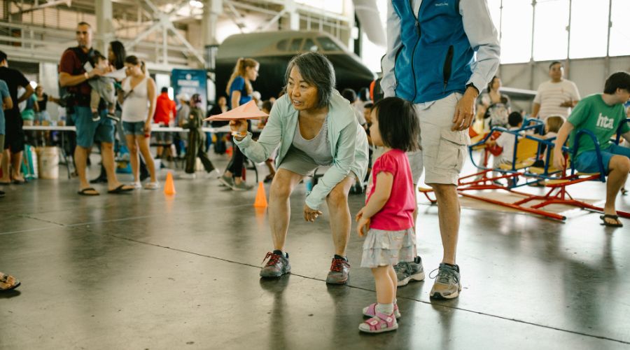 Grandparents showing granddaughter how to fly a paper plane on Museum Day at PHAM.